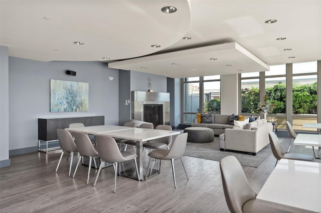 dining area featuring a wall of windows, a fireplace, and wood finished floors