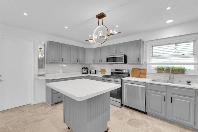 kitchen featuring light countertops, decorative backsplash, gray cabinets, appliances with stainless steel finishes, and a sink