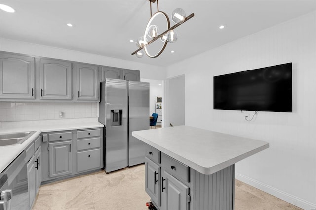 kitchen with backsplash, a kitchen island, light countertops, gray cabinets, and appliances with stainless steel finishes