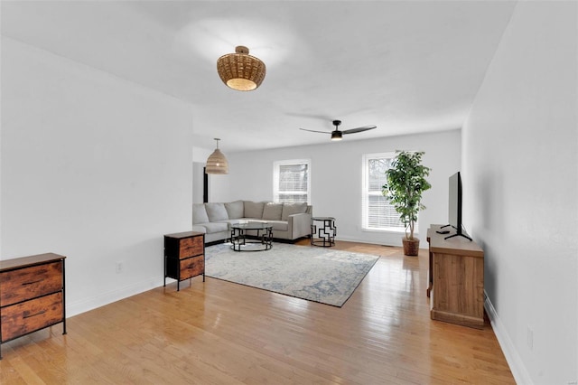 living room featuring ceiling fan, baseboards, and light wood-style floors