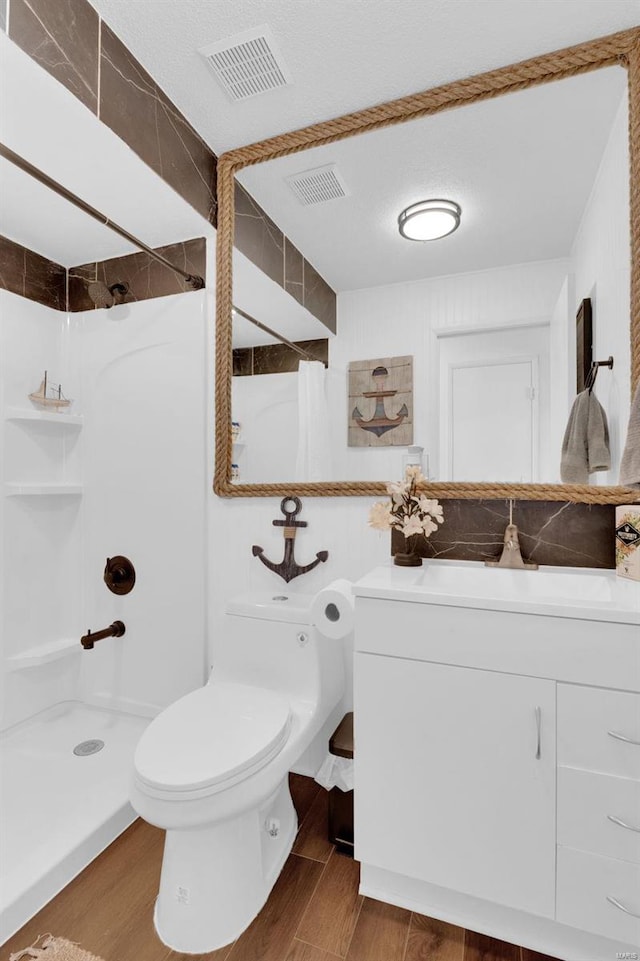 bathroom with visible vents, a stall shower, toilet, and wood finished floors