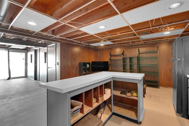 basement with freestanding refrigerator and wood walls