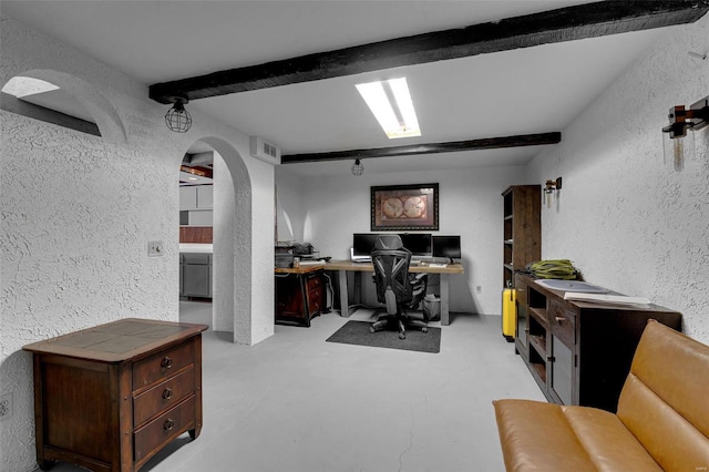 office area featuring visible vents, concrete flooring, beam ceiling, a textured wall, and arched walkways