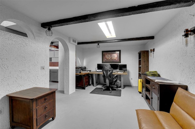 office featuring arched walkways, concrete flooring, and a textured wall