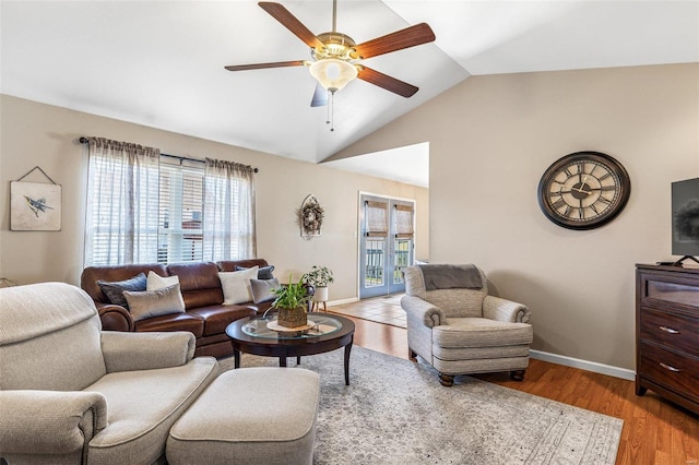 living room featuring vaulted ceiling, light wood-style flooring, a ceiling fan, and baseboards