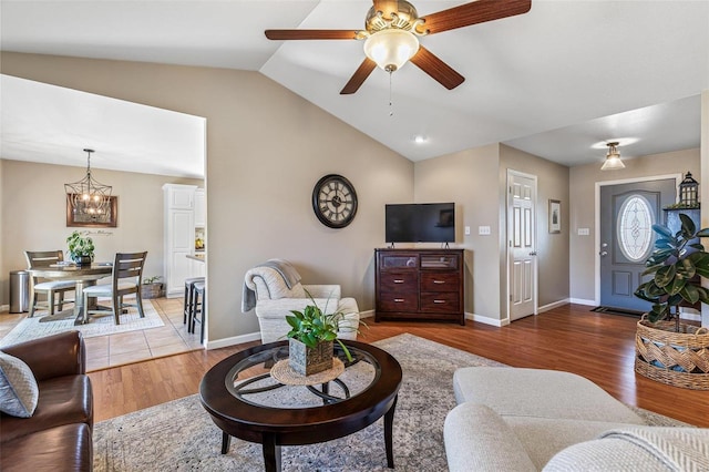 living room with baseboards, lofted ceiling, wood finished floors, and ceiling fan with notable chandelier