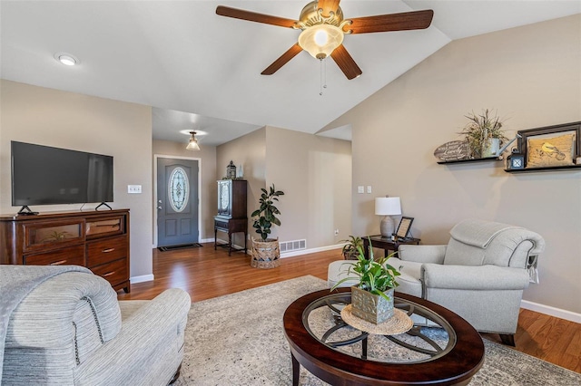 living room with a ceiling fan, wood finished floors, visible vents, baseboards, and vaulted ceiling