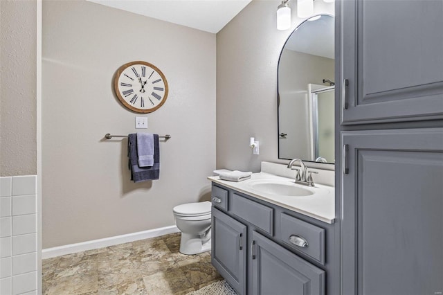 full bath with a shower with shower door, toilet, stone finish flooring, baseboards, and vanity
