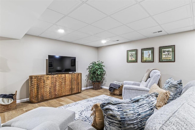 living area featuring a paneled ceiling, wood finished floors, visible vents, and baseboards