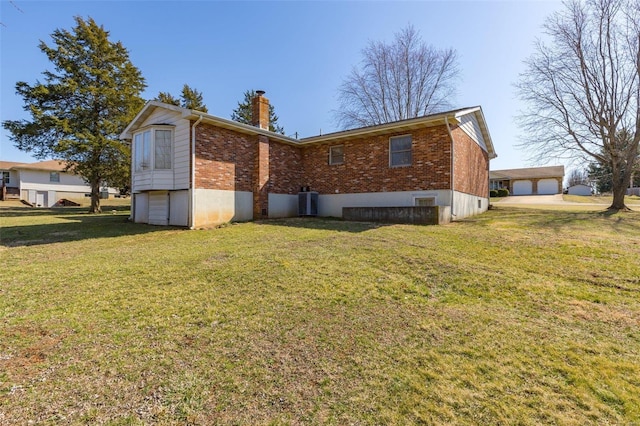 view of side of property featuring a yard, a garage, brick siding, central AC unit, and a chimney