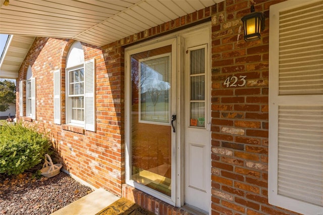 property entrance featuring covered porch and brick siding