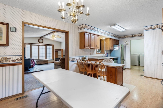 kitchen with a textured ceiling, washing machine and clothes dryer, and wallpapered walls