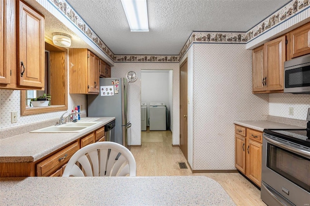 kitchen with visible vents, wallpapered walls, appliances with stainless steel finishes, independent washer and dryer, and a textured ceiling