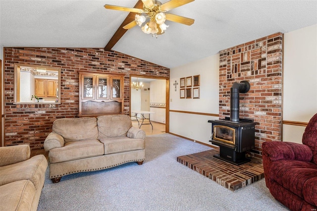 carpeted living room with brick wall, ceiling fan, lofted ceiling with beams, a wood stove, and a textured ceiling