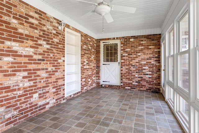 unfurnished sunroom featuring a ceiling fan