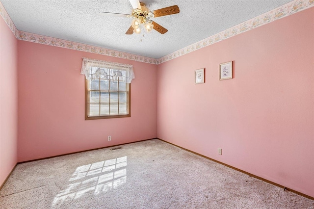 carpeted empty room featuring baseboards, visible vents, a textured ceiling, and ceiling fan