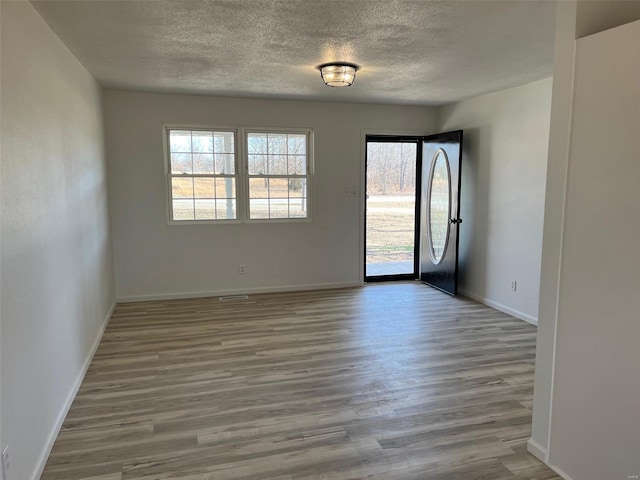 spare room with baseboards, a textured ceiling, and wood finished floors