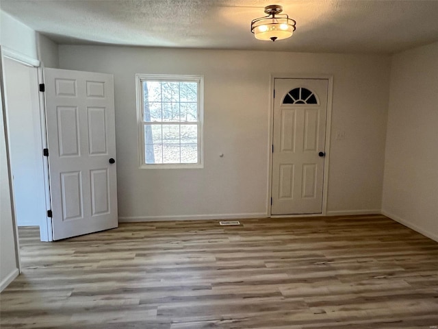 foyer with baseboards, a textured ceiling, and wood finished floors