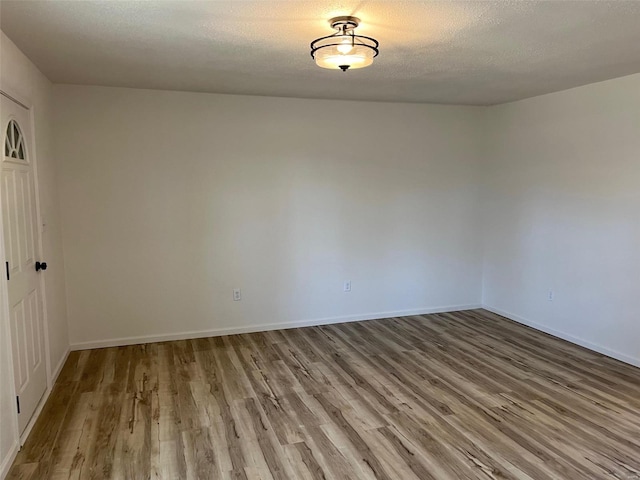 unfurnished room with wood finished floors, baseboards, and a textured ceiling