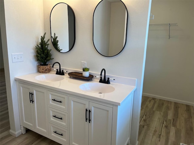 bathroom featuring double vanity, wood finished floors, baseboards, and a sink