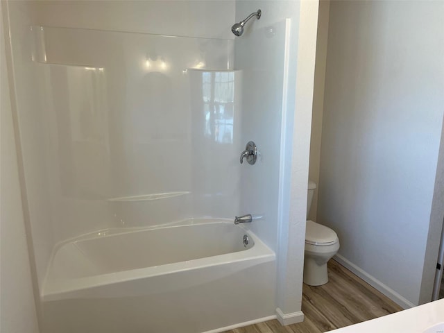 bathroom featuring  shower combination, toilet, wood finished floors, and baseboards