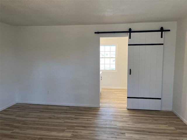 interior space featuring a barn door, a textured ceiling, and wood finished floors