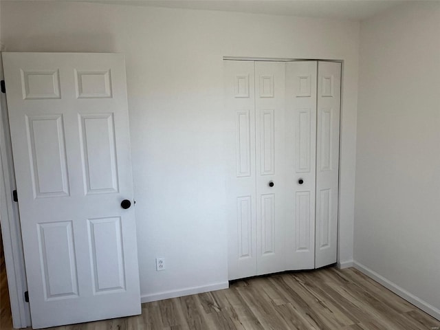 unfurnished bedroom featuring a closet, baseboards, and wood finished floors