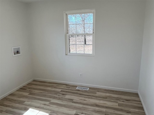 spare room featuring wood finished floors, visible vents, and baseboards