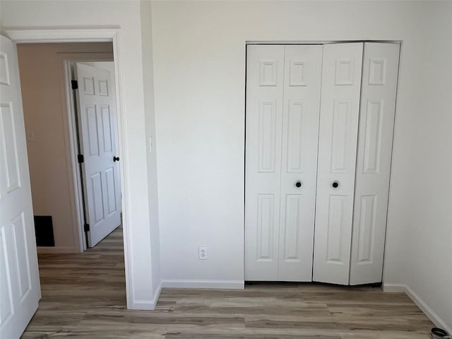 unfurnished bedroom featuring a closet, baseboards, and light wood-style floors