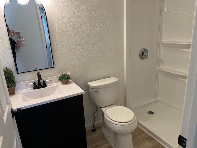 full bath with toilet, vanity, a shower stall, and wood finished floors