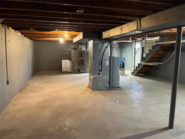 unfinished basement featuring stairs, heating unit, and water heater