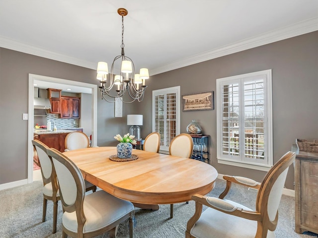 carpeted dining room with crown molding, baseboards, and a chandelier