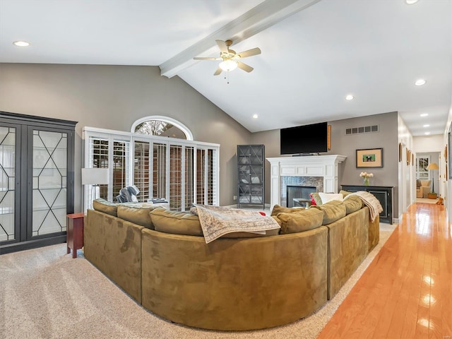 living room featuring visible vents, a ceiling fan, a high end fireplace, recessed lighting, and vaulted ceiling with beams