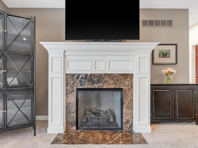 details featuring carpet flooring, baseboards, visible vents, and a high end fireplace