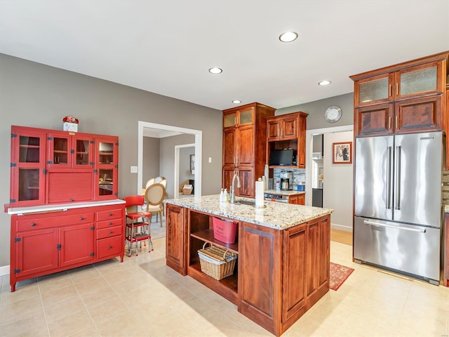 kitchen with open shelves, light stone counters, high end refrigerator, recessed lighting, and a sink