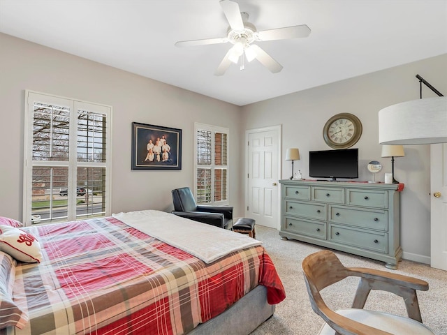 bedroom featuring light colored carpet, baseboards, and a ceiling fan