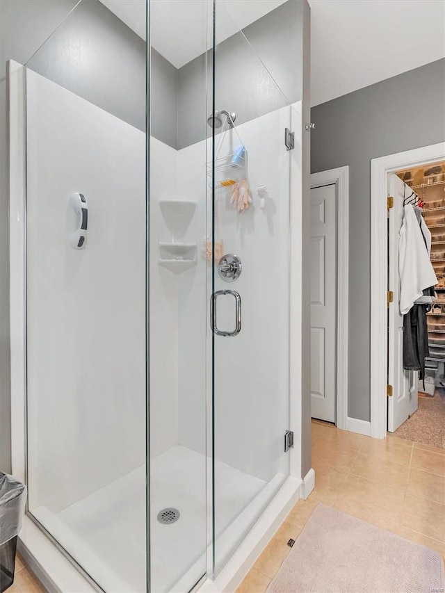 full bath featuring tile patterned floors, a spacious closet, and a shower stall