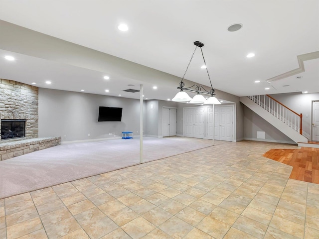 unfurnished living room with light carpet, recessed lighting, stairway, a fireplace, and baseboards