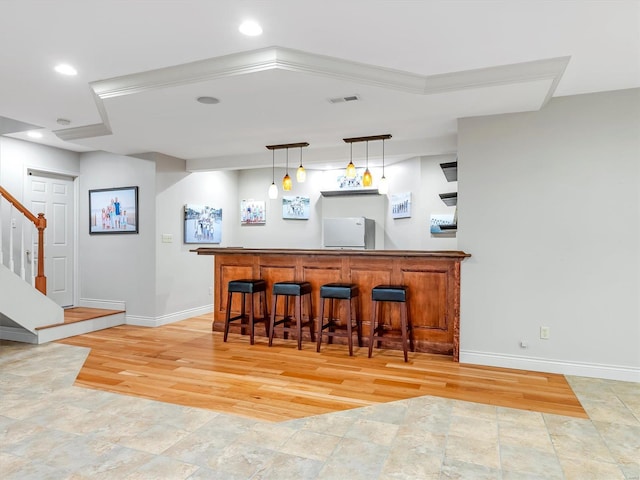 bar with baseboards, visible vents, stairs, bar area, and fridge