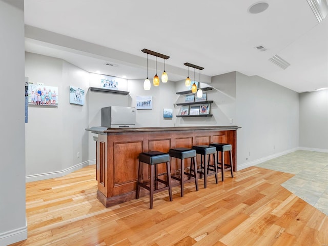 bar with light wood finished floors, visible vents, a dry bar, and pendant lighting