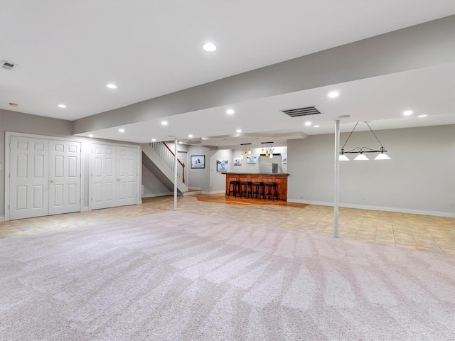 finished basement featuring light carpet, visible vents, recessed lighting, and a bar