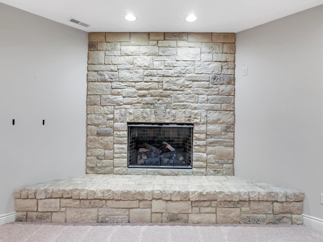 details featuring visible vents, baseboards, a stone fireplace, and carpet flooring