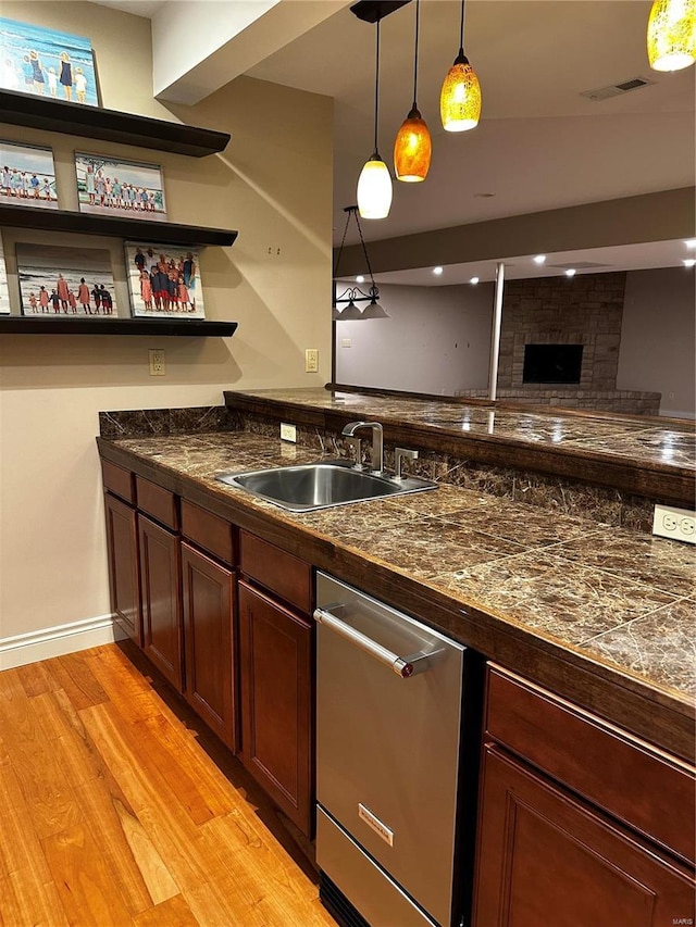 bar featuring visible vents, light wood-type flooring, pendant lighting, a sink, and stainless steel dishwasher