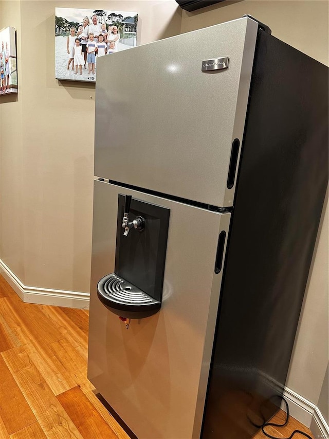 details featuring light wood-type flooring, freestanding refrigerator, and baseboards