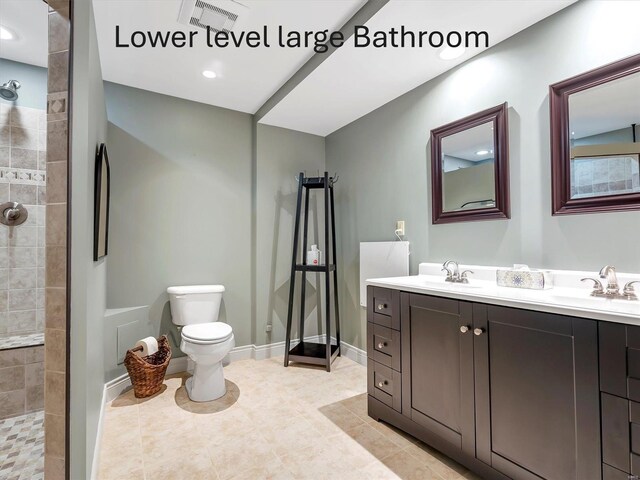 full bath featuring a tile shower, visible vents, toilet, and a sink