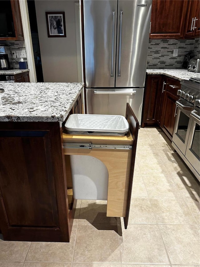 kitchen featuring dark brown cabinets, decorative backsplash, light stone countertops, and high end appliances