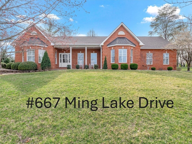 ranch-style house featuring a front lawn, brick siding, and a shingled roof