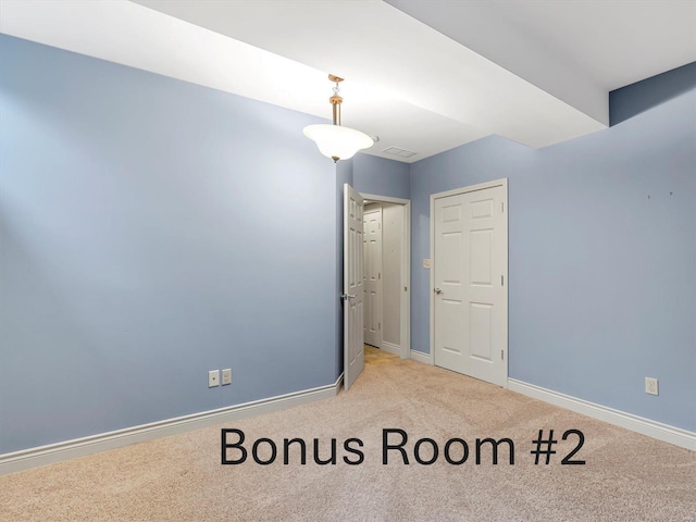 unfurnished room with light colored carpet and baseboards