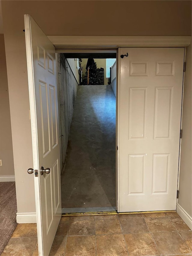 hallway featuring baseboards and stone finish floor