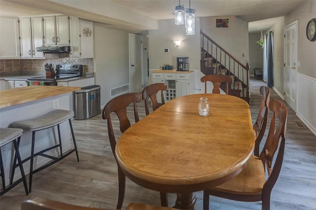 dining room featuring visible vents, stairway, baseboards, and wood finished floors